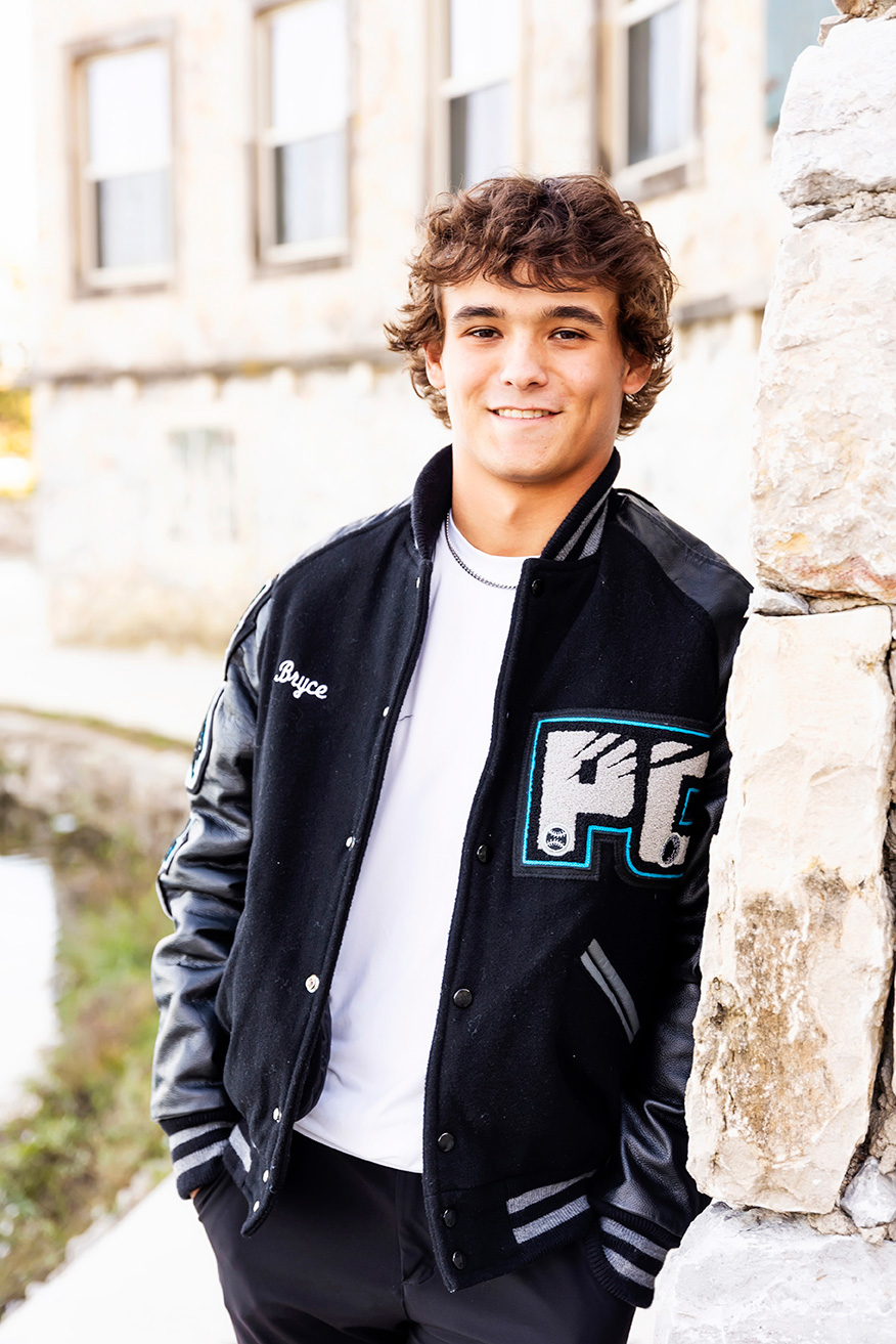 senior photos frisco tx of a guy smiling wearing his lettermans jacket