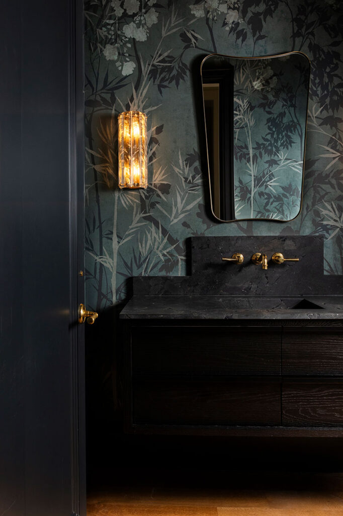 Dark and moody Dallas guest bathroom with a dramatic stone sink, layered textures, and thoughtful interior design details