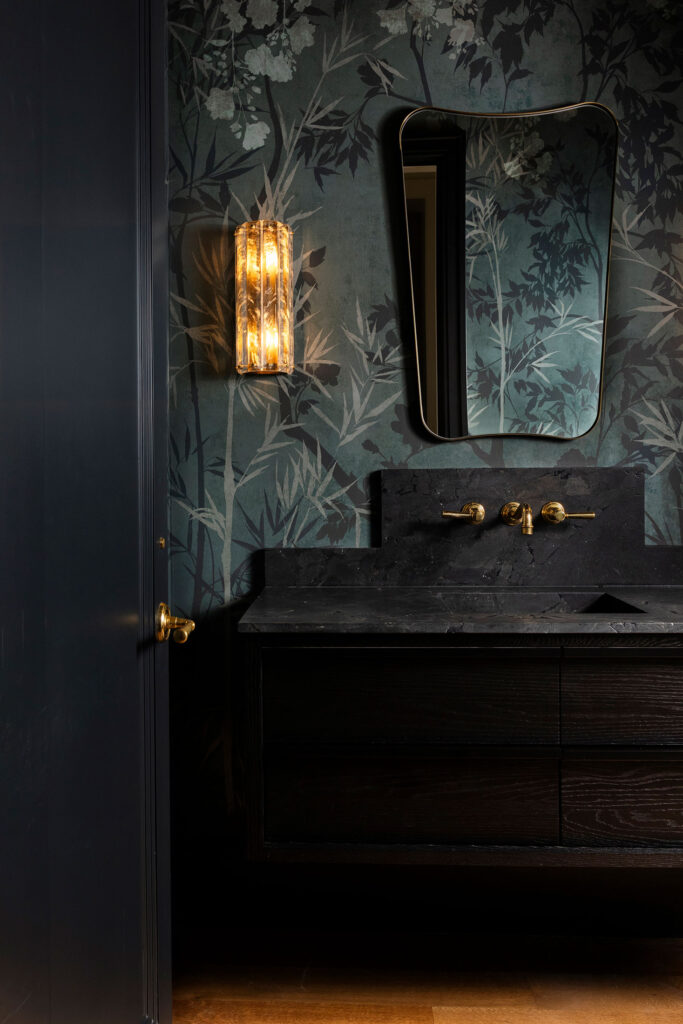 dark bathroom with custom wallpaper and brass accents