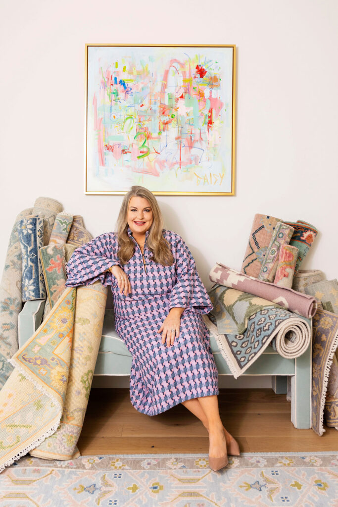 updated headshot of designer surrounded by rugs