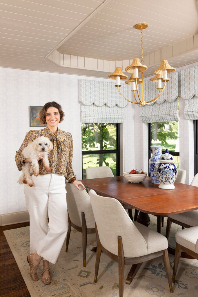 designer holding her dog in front of a dining room